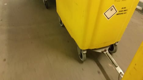 yellow medical waste bins wheeled down corridor