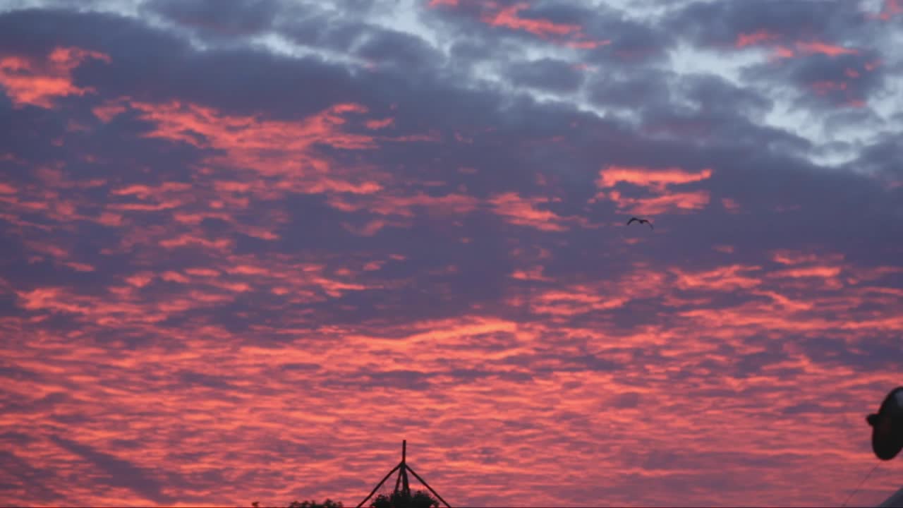 Stunning pink sky and blue feather clouds above still empty festival grounds on Glastonbury early morning before a sun rise. Shops are closed; there is nobody on roads. Birds are flying. Footage in HD