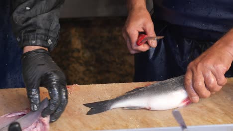 fisherman cleaning and filleting fresh sea bass at the market