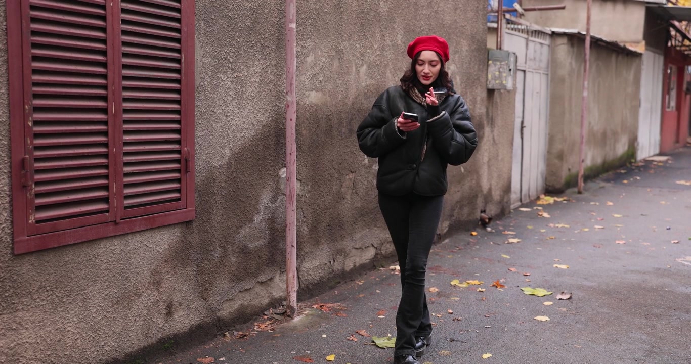 Donna con abiti caldi fuma e scrive messaggi sullo smartphone per strada