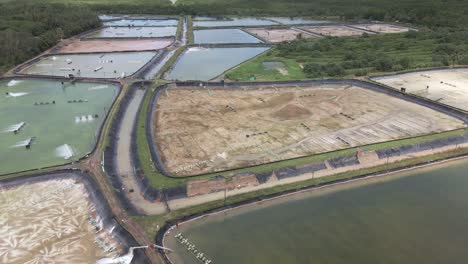 Toma-Aérea-De-Una-Granja-Camaronera-Industrial-En-El-Sudeste-Asiático-Con-Diferentes-Piscinas-Con-Agua-Y-Algunas-Sin-Agua