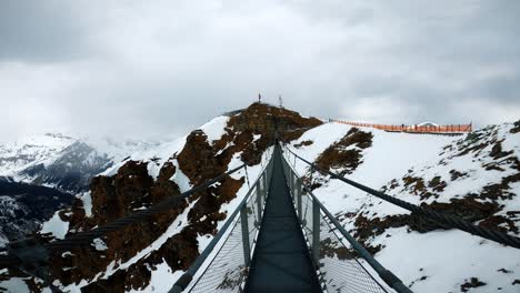 walking over a hanging bridge up in snowy mountains