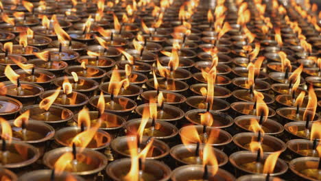 rows of candles flickering slowly in a monastery in nepal