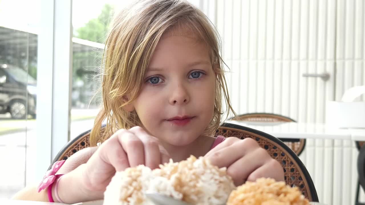 Bambina che mangia il dessert in un caffè