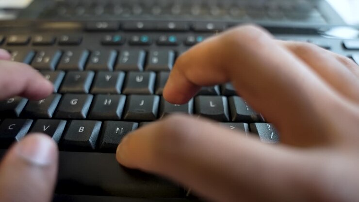 An individual Typing on computer keyboard, captured in a close-up video, symbolizing the realm of digital work and diverse task management on computers