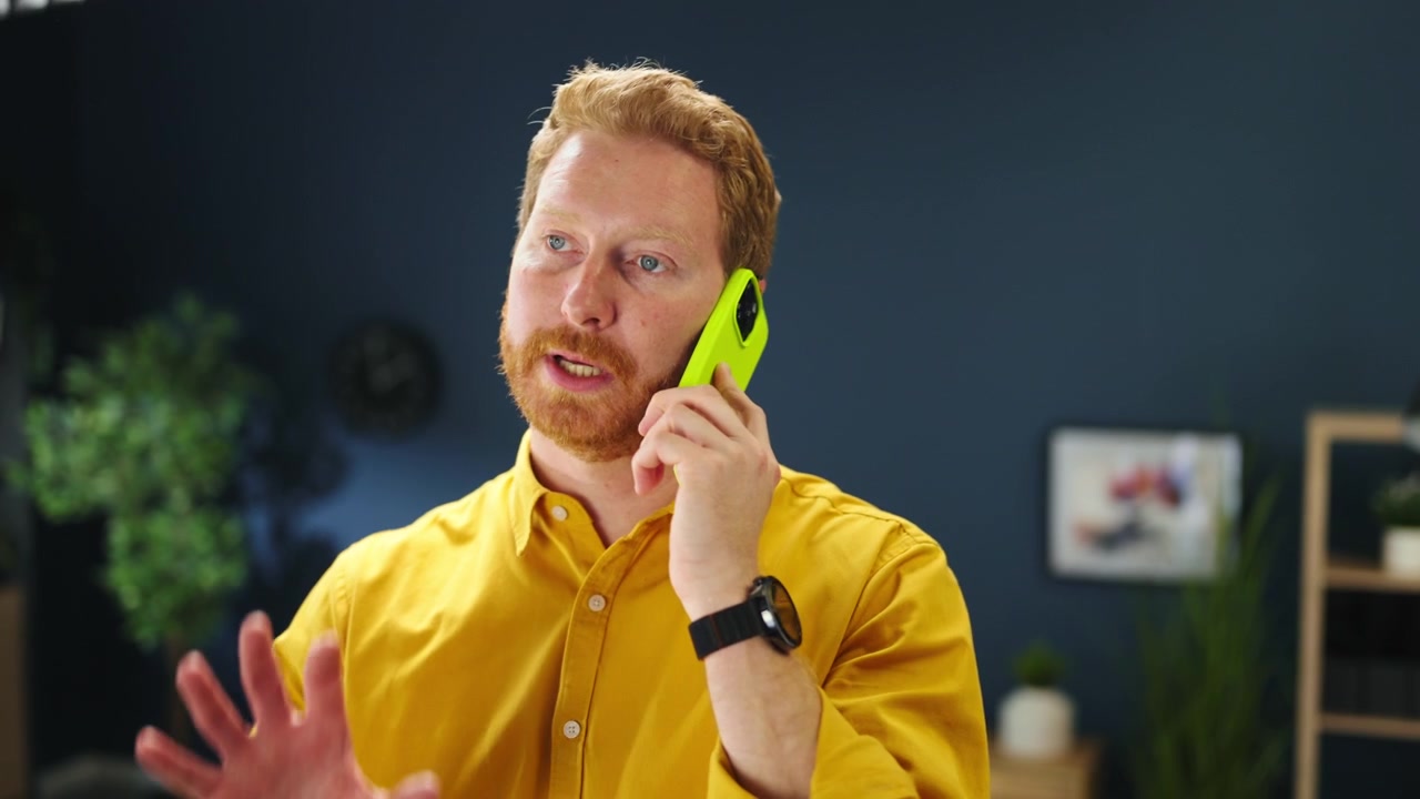 Uomo dai capelli rossi che parla allo smartphone in un ufficio moderno