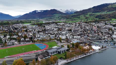 Ciudad-De-Lachen-Con-Centro-Deportivo-Y-Puerto-De-Yates,-Descripción-General-Del-Establecimiento-Con-Drones,-Pueblo-Suizo-En-El-Paisaje-De-Montaña