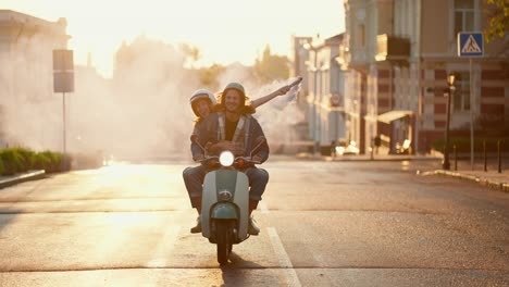 A-happy-guy-with-long-curly-hair-in-a-denim-jacket-rides-on-his-green-moped-with-a-girl-in-a-white-moped-helmet-who-is-holding-a-blue-fire-in-her-hands-that-leaves-behind-a-gray-haze-along-the-summer-morning-street