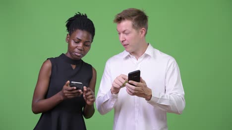 Two young multi-ethnic business couple using phone together