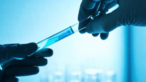 close-up of a hand holding a test tube with blue liquid