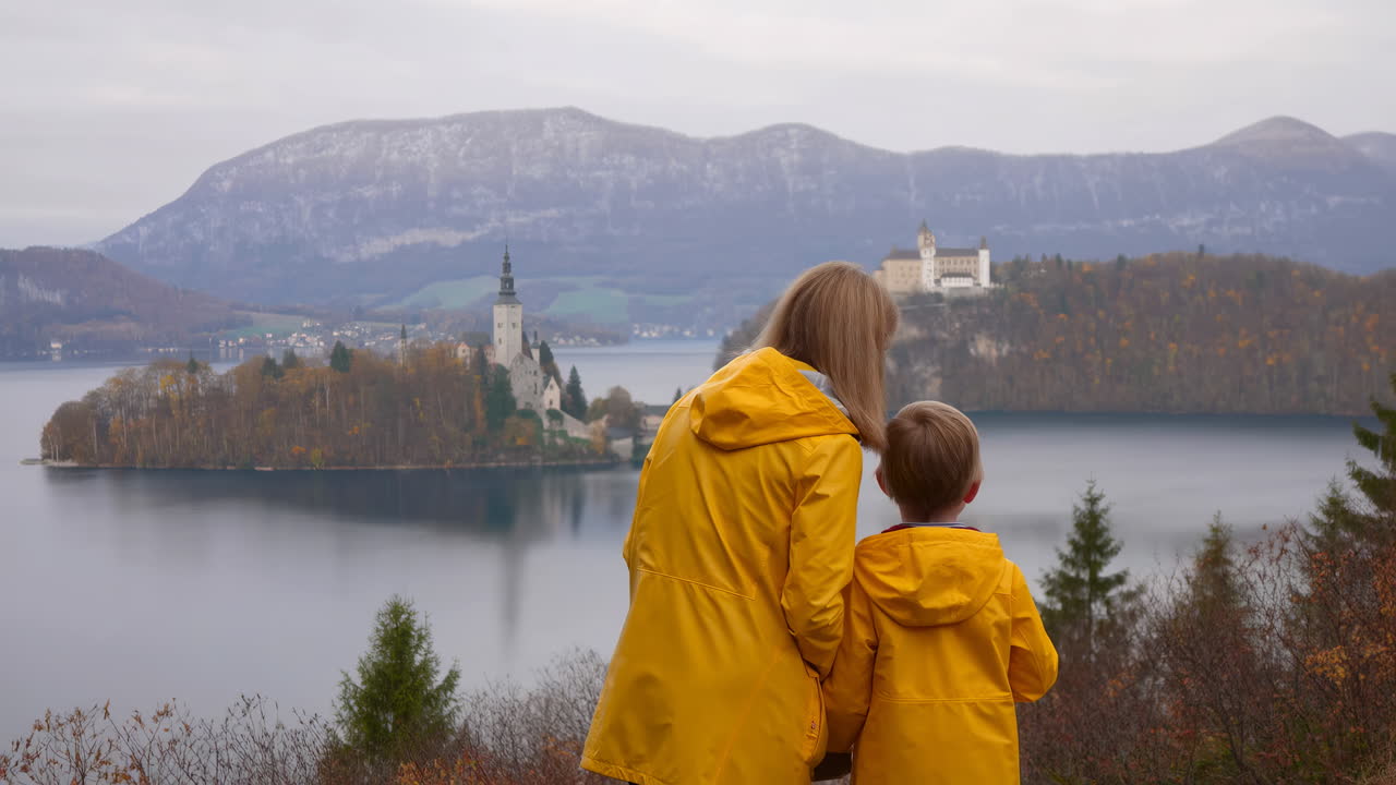 Mãe e filho admirando um castelo em uma ilha em um lago