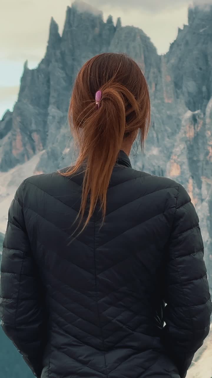 Rear view of a woman in a jacket admiring a spectacular mountain panorama during a hike, Dolomites