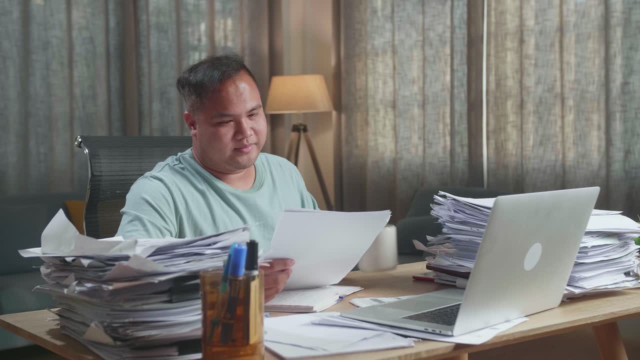 Fat Asian Man With Laptop Drinking Water While Working Hard With Documents At The Office