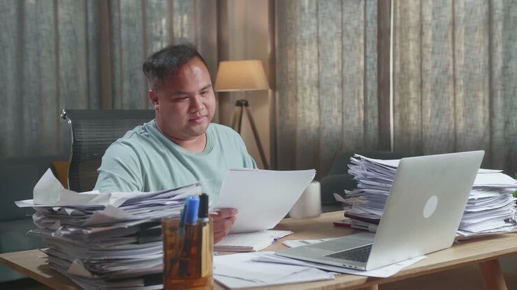 Fat Asian Man With Laptop Drinking Water While Working Hard With Documents At The Office