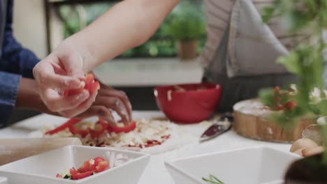 manos de dos amigas adolescentes diversas preparando pizza juntas en cámara lenta