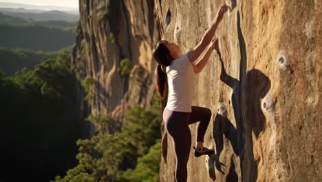 woman bouldering on a rock face at sunset