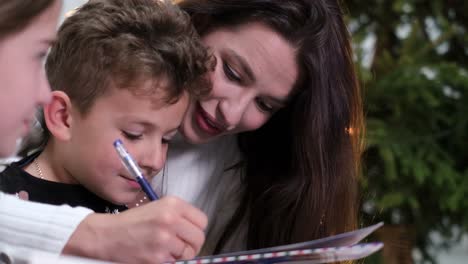 mom with kids writes a letter to santa claus mom with kids writes a letter to santa claus happy family on new years eve on the background of the christmas tree christmas comfort in the house