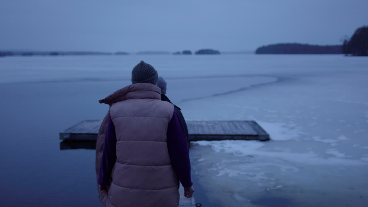 An ice bathing couple approach the frozen bathing jetty