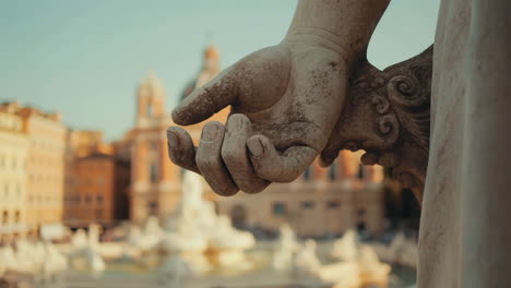 close-up of a roman statue's hand with the trevi fountain in the background