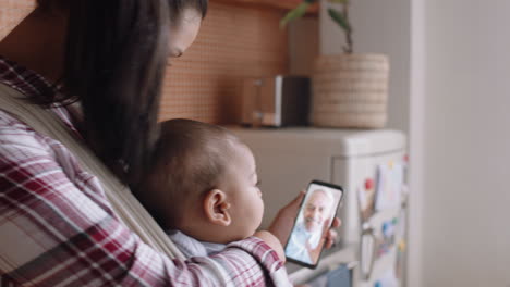 young mother and baby having video chat with grandfather using smartphone waving at granddaughter enjoying family connection