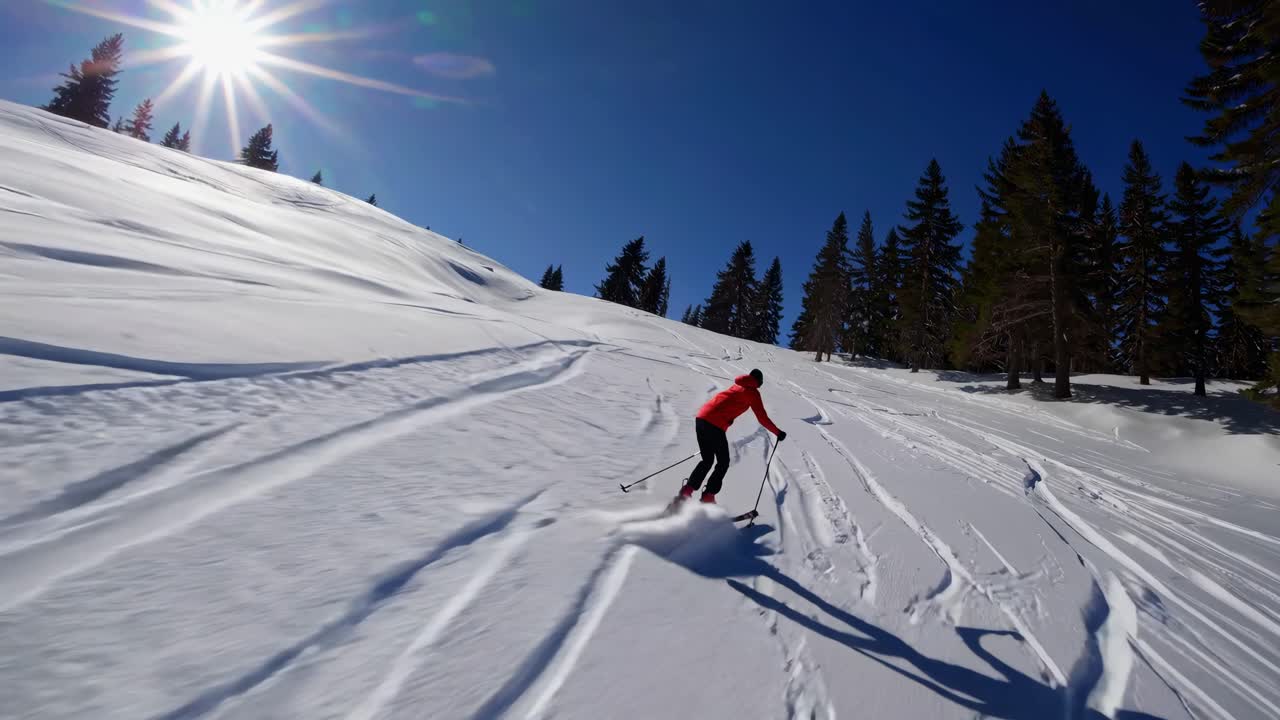 Un video dinamico cattura uno sciatore in giacca rossa che scende lungo un pendio innevato