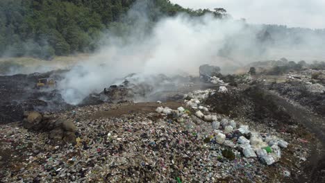 aerial orbits burning garbage smoke in large landfill site, guatemala