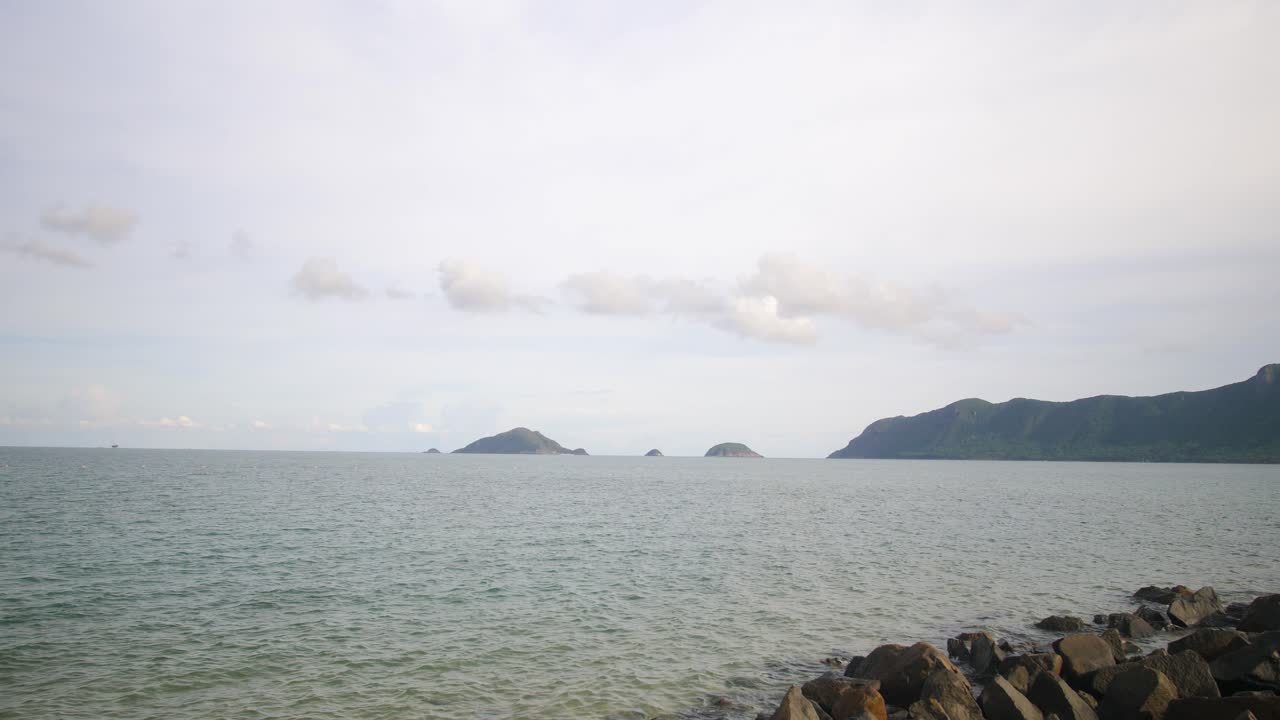 Rocky coastline with calm sea and distant green mountains on Con Dao Island, Vietnam