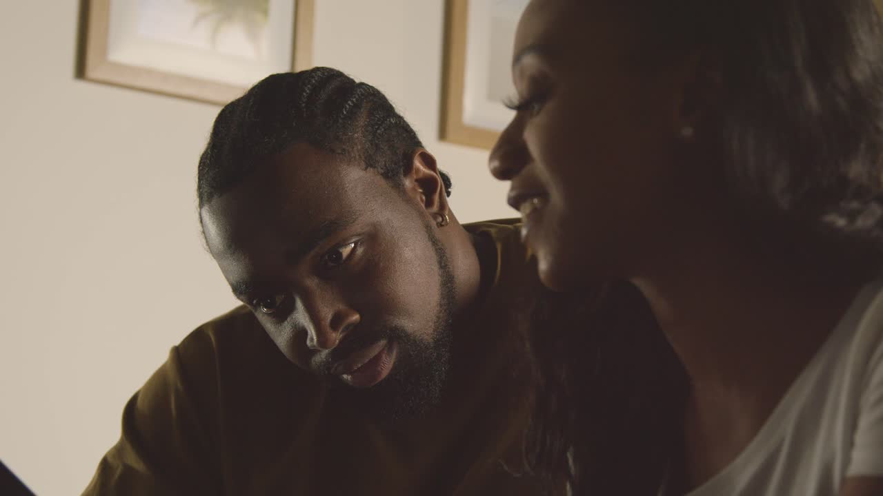 pareja joven relajándose en casa por la noche en el dormitorio mirando el teléfono móvil juntos