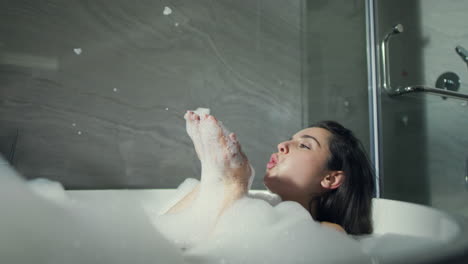 Niña-Sonriente-Soplando-Espuma-En-La-Bañera-Del-Baño.-Hermosa-Mujer-Tomando-Baño-De-Burbujas