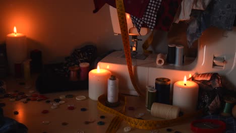 vintage background shot of a sewing machine, threads, buttons and candles, with dust flying around