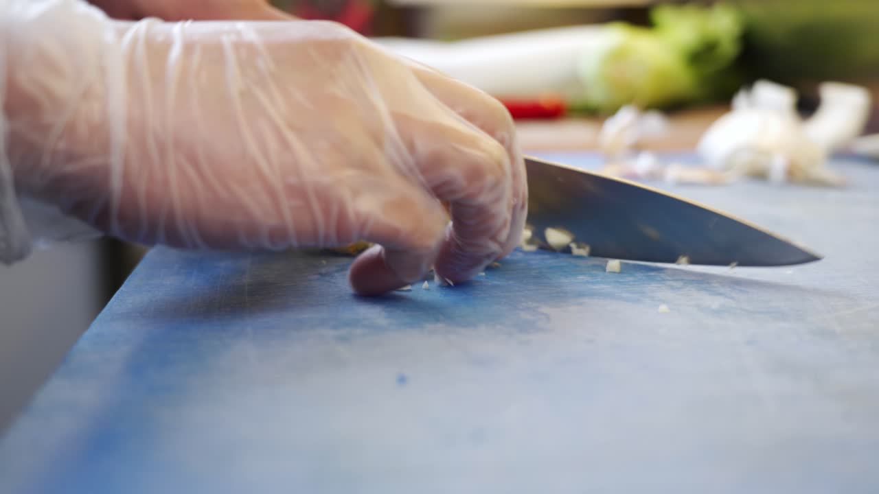 cortar ajo en trozos pequeños en una tabla de corte azul en un restaurante de sushi