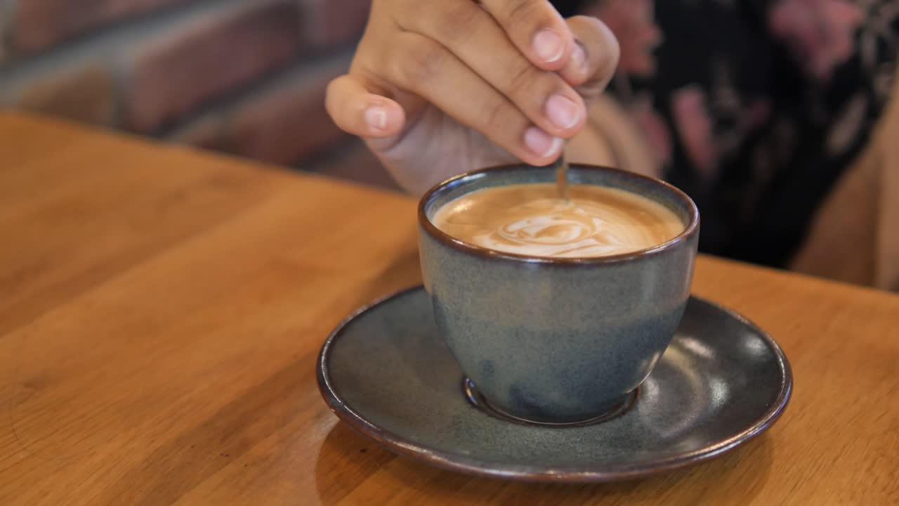 A woman stirs her latte in a cafe