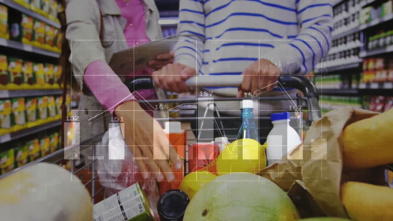 Coppia che spinge un carrello della spesa mentre scansiona un tablet e analizza grafici lineari che prevedono i trend del retail