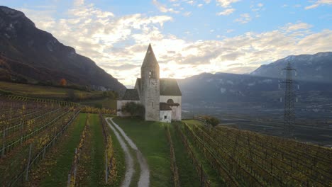 Aerial-Drone-Over-a-medieval-church-in-the-middle-of-the-Vineyards-in-Autumn-in-South-Tyrol