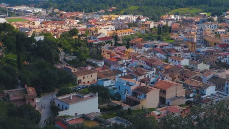 Ein-Schwenkblick-über-Die-Schönen-Und-Farbenfrohen-Alten-Häuser-Mit-Dem-Grünen-Wald-Der-Stadt-Capdepera,-Mallorca