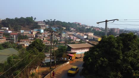 aerial view low over traffic, toward traditional homes in yaounde, cameroon, africa