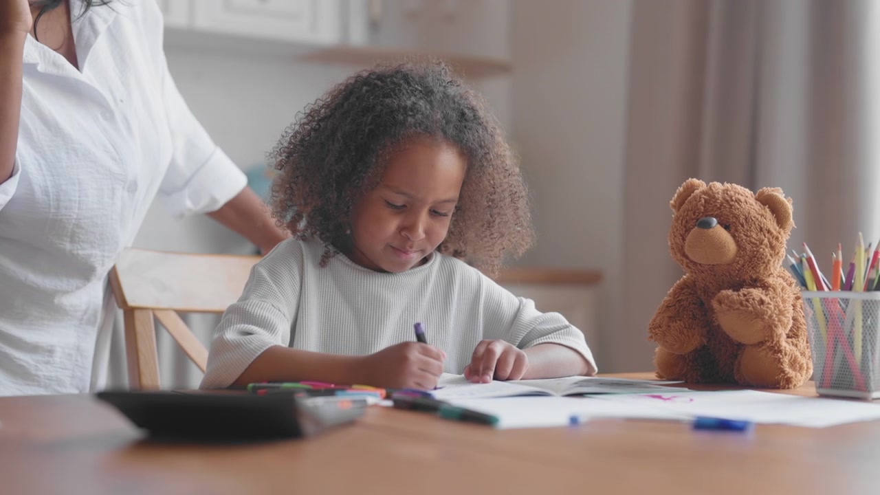 Young Girl Drawing in Coloring Book at Home Table