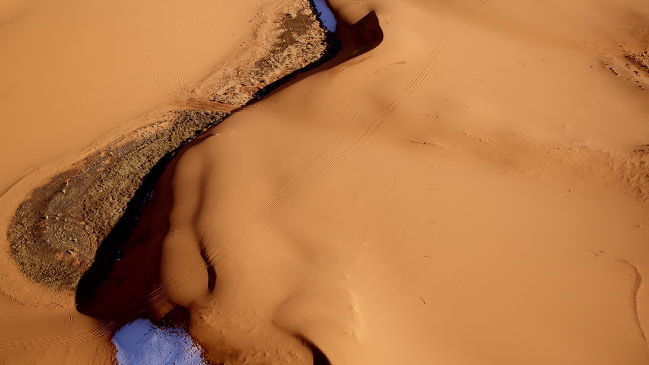 Surreal drone shot looking down on the mesmerizing shapes and colors of the pink sand dunes in southern utah