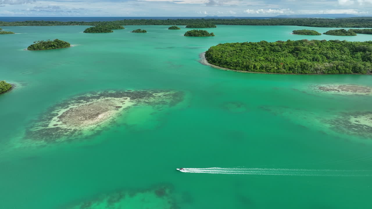 Boat driving through clear water with surrounding small islands in Vona Vona Lagoon, Solomon Islands