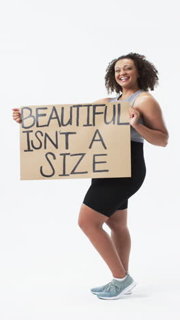 vertical video: smiling plus size woman holding sign promoting body positivity