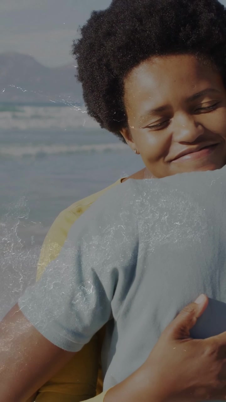 Video verticale: Donna che si appoggia a un uomo e lo abbraccia in spiaggia, inquadratura che rivela l'oceano per pubblicità di viaggi.