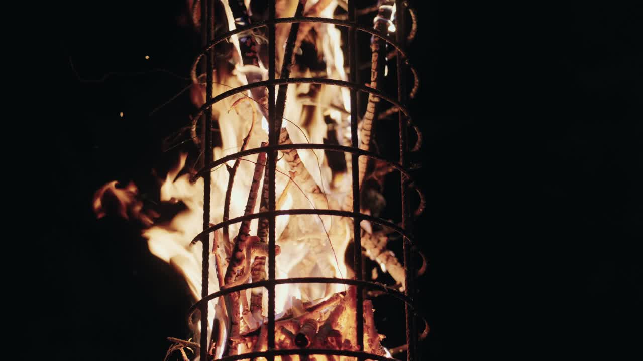 flames consuming wood inside metal tower in darkness