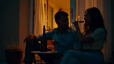 couple enjoying wine on a balcony at night