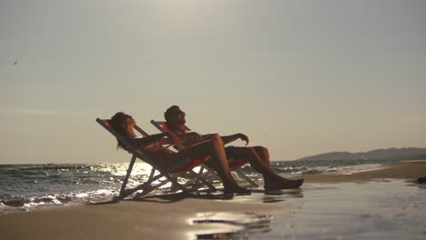una pareja relajándose en la playa al atardecer.