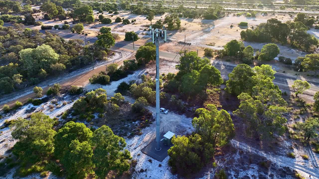 Pan drone shot of telco tower surrounded with green bushes and trees during daytime.