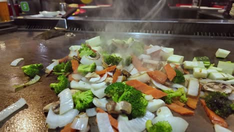 close-up of mixed vegetables sizzling and steaming on hot teppanyaki grill, asian food