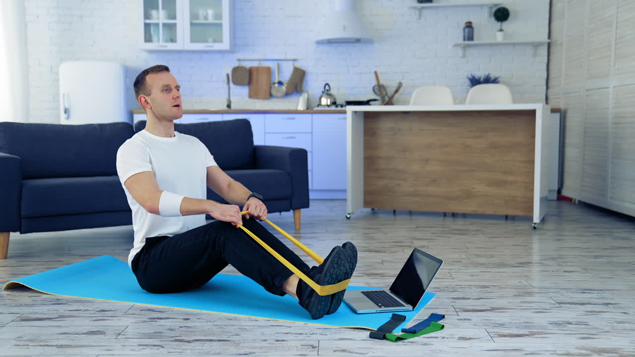 Man doing exercise with online tutorial. Attractive young man doing exercising at home