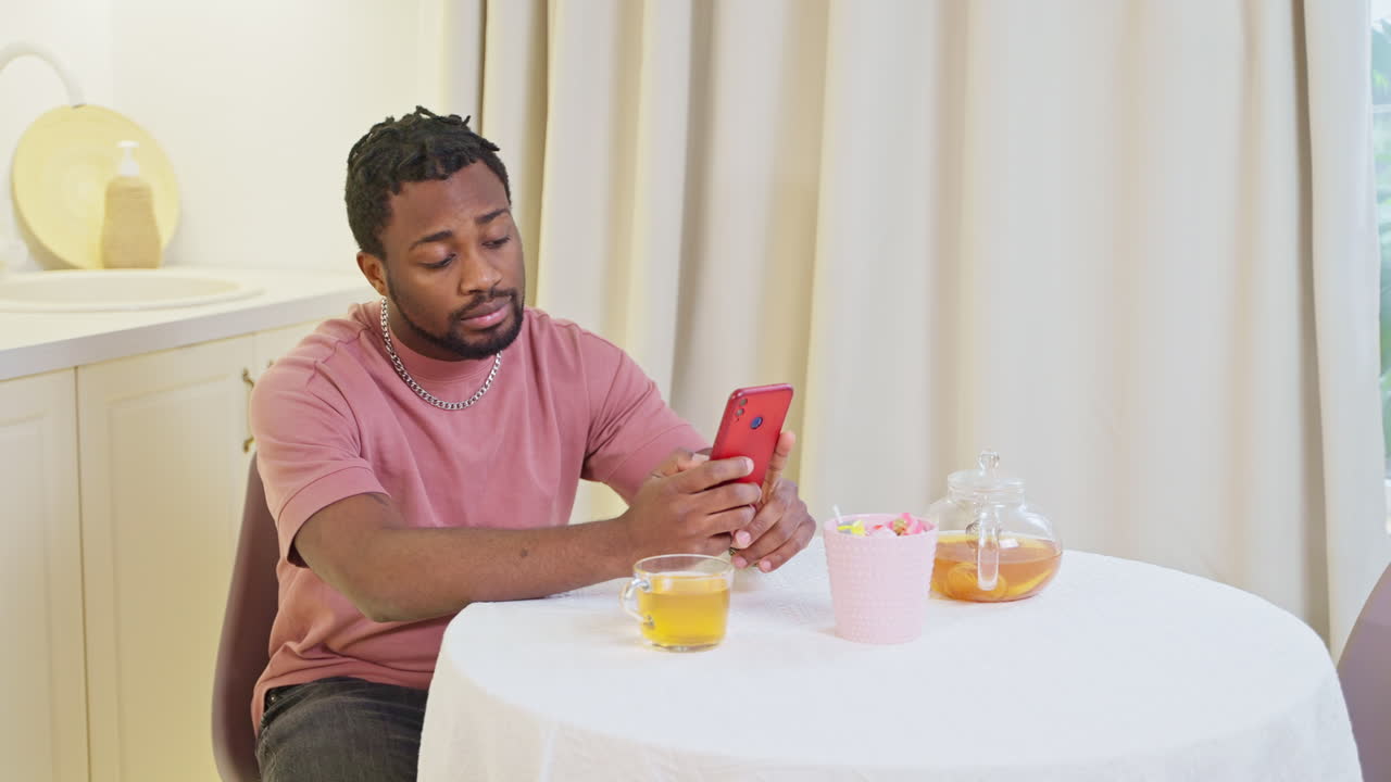 Man using smartphone at kitchen table