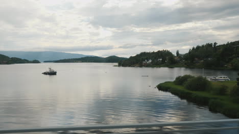 Viajar-A-Través-De-Noruega-A-Lo-Largo-De-La-Orilla-De-Un-Hermoso-Lago-Una-Vista-Desde-La-Ventana-De-Un-Automóvil