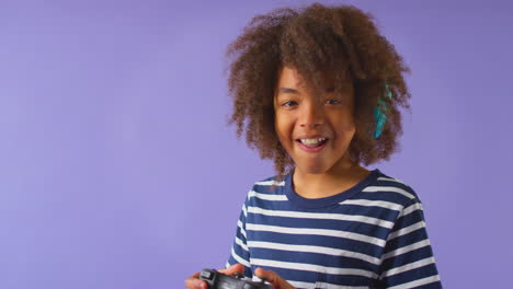 Foto-De-Estudio-De-Un-Niño-Jugando-Con-Un-Controlador-Contra-Un-Fondo-Morado